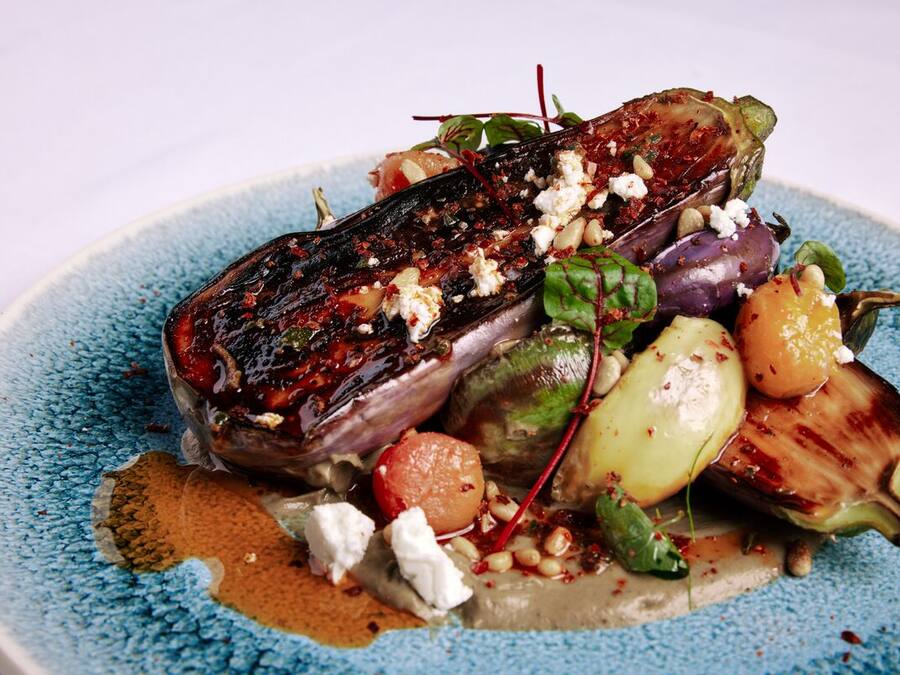 A plate of food with grilled eggplant, feta cheese, and various vegetables.