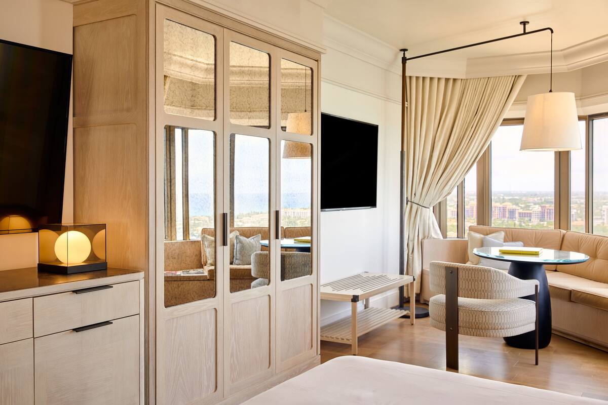 A modern hotel room with a large wardrobe, a sofa, a round table, and a TV.