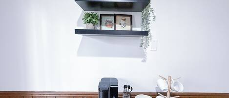 Una encimera de cocina con una cafetera, un expositor de cápsulas de café y un organizador para tazas de café.