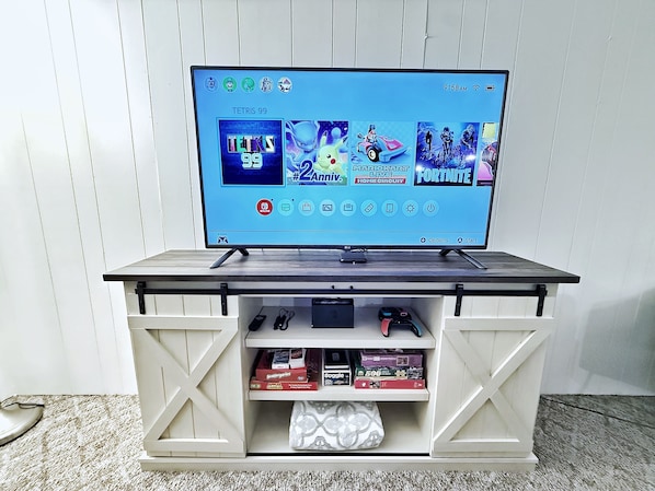 Een spelconsole op een plank met spelletjes en controllers.