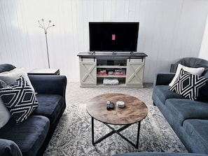 Een moderne woonkamer met twee banken, een salontafel, een televisie en een opbergmeubel.