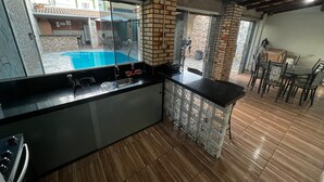 A kitchen with a built-in stove, a sink, and a view of a swimming pool. - House with pool and barbecue. (Cuiaba)