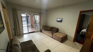 A living room with a sofa, a television, and a sliding glass door leading to an outdoor area. - House with pool and barbecue. (Cuiaba)