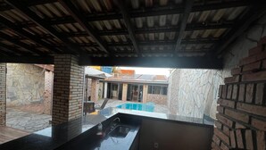 A kitchen with a black countertop and a view of a backyard with a pool. - House with pool and barbecue. (Cuiaba)