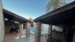 A covered outdoor area with stone flooring, a pool, and a barbecue setup. - House with pool and barbecue. (Cuiaba)