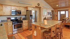 A spacious kitchen with wooden cabinets, stainless steel appliances, and a central island with bar stools.