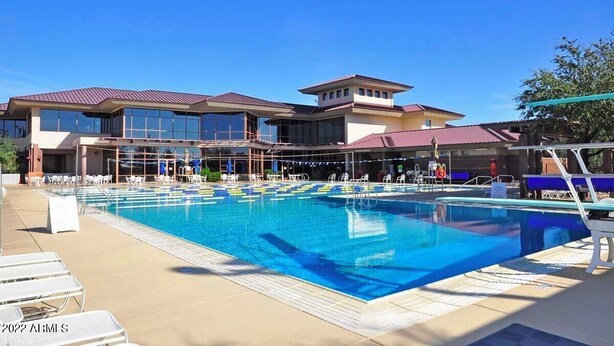 A swimming pool with lounge chairs and a building with multiple windows and a red roof. - NW Phoenix in Gated Anthem Country Club - House + Guest Casita (Phoenix (Anthem))
