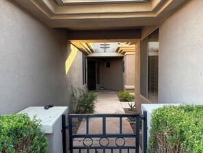 A building entrance with a gated pathway, a small garden area, and a door leading to a building interior.