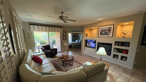 A living room with a sofa, a coffee table, a TV, and a fireplace. - NW Phoenix in Gated Anthem Country Club - House + Guest Casita (Phoenix (Anthem))
