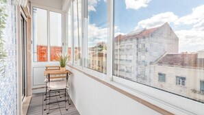 Un balcon avec une table en bois, des chaises et un pot de fleurs.