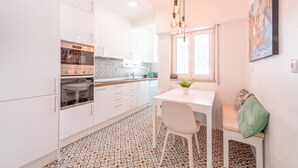 Une cuisine de taille réduite avec des meubles blancs, un four encastré et un sol à motifs.