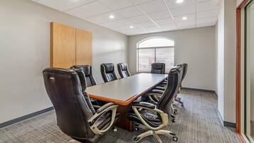 Une salle de conférence dotée d’une longue table et de nombreuses chaises, d’un sol recouvert de moquette et d’un mur décoratif en bois.