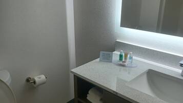 Un baño con un lavamanos blanco, un espejo, un inodoro y un estante con toallas.