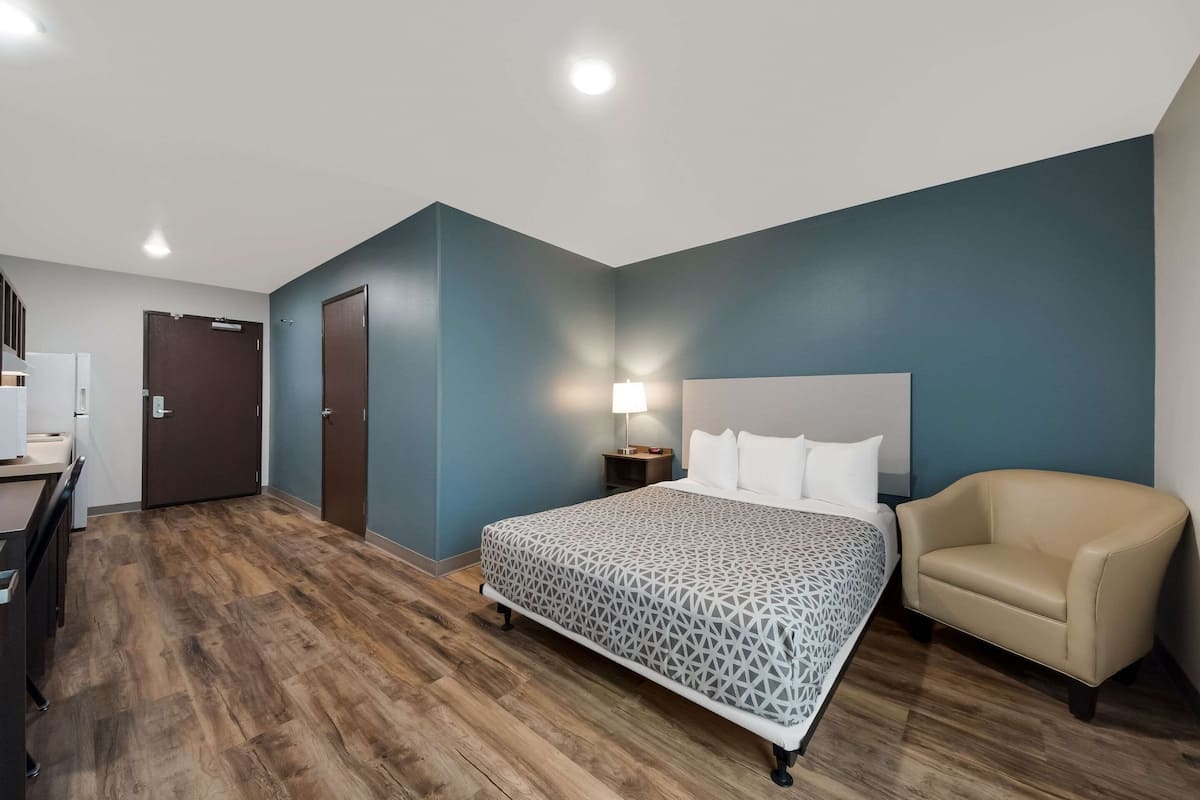 Una camera d'albergo con un letto, una sedia, una scrivania e una porta.