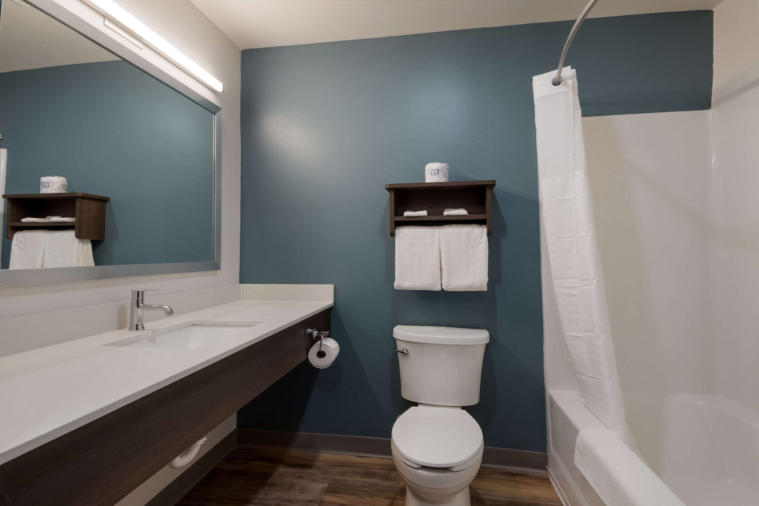 Een badkamer met een witte wastafel, een toilet, een douchegordijn en een spiegel.