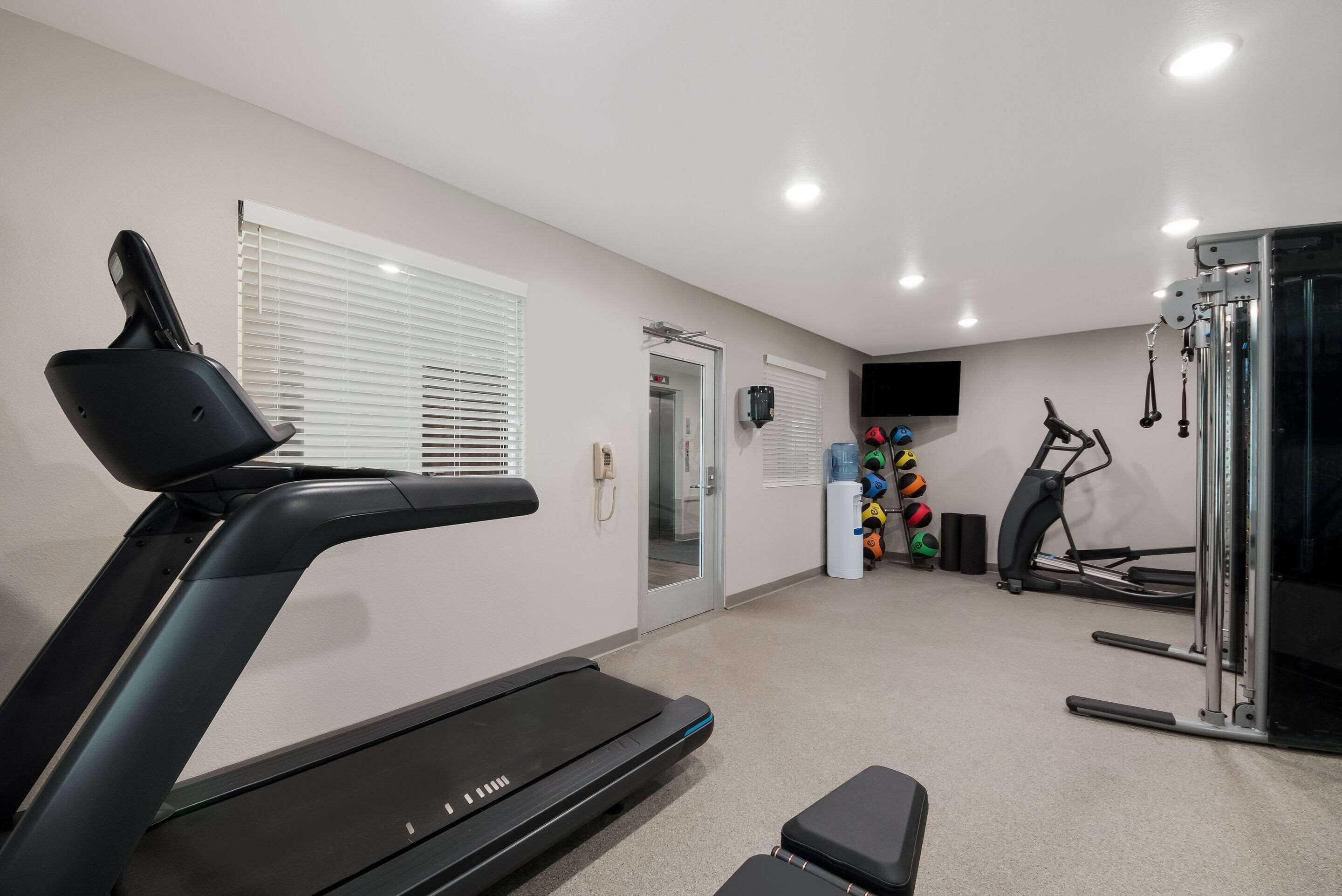 Un gimnasio en casa con cinta de correr, elíptica y equipo de levantamiento de pesas.