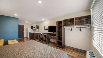 A modern bedroom with a bed, desk, TV, and built-in storage.