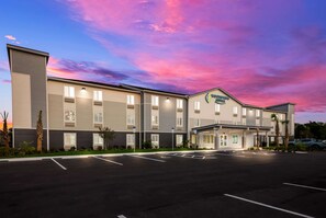 A hotel with a modern design, featuring a parking lot and a well-lit facade. - WoodSpring Suites Inverness (Inverness)