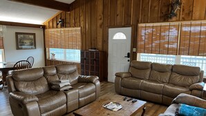 Ein geräumiges Wohnzimmer mit Ledersofas, einem Holztisch und einem Essbereich mit Holztisch und Stühlen.