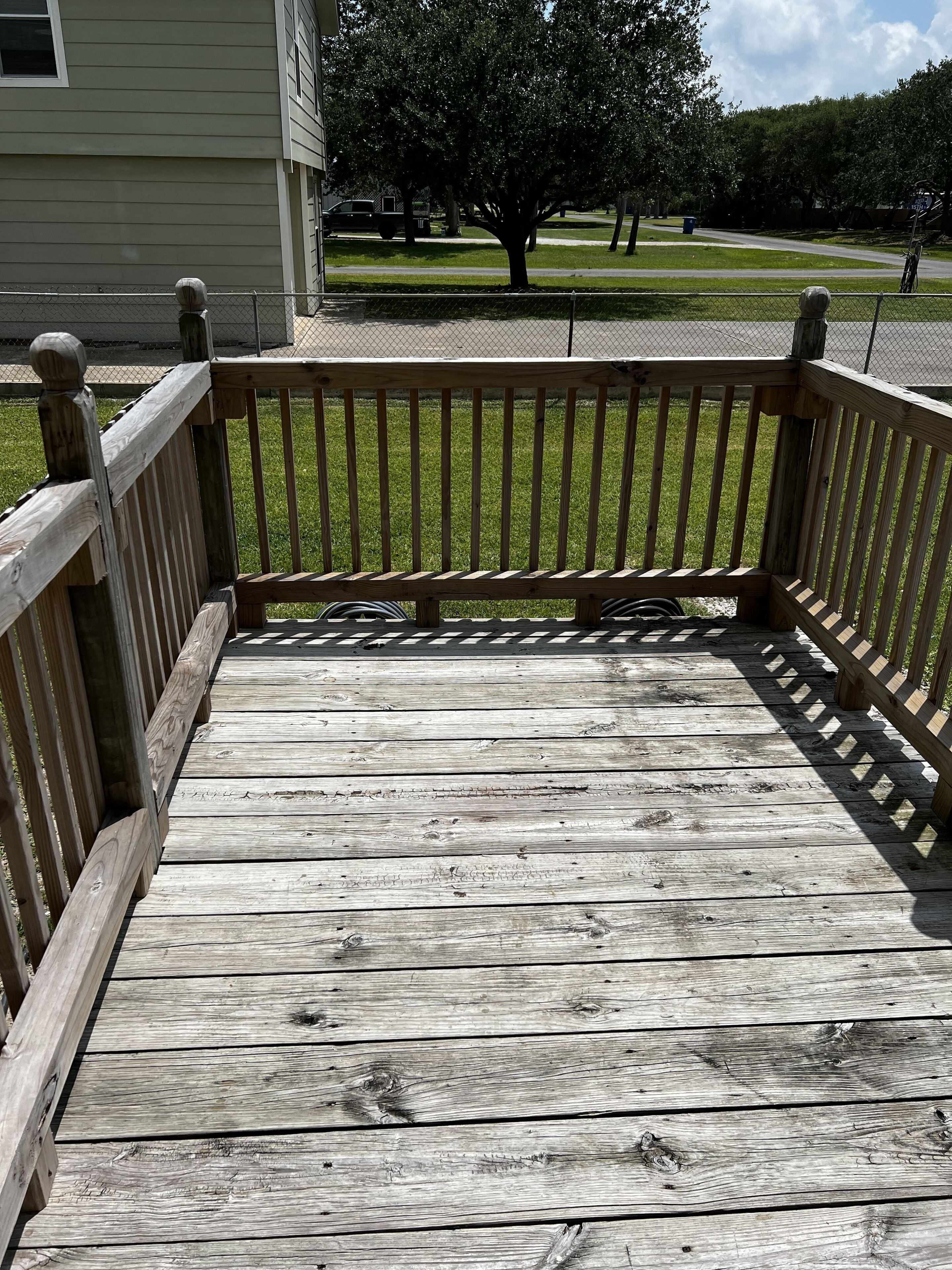 A wooden deck with a railing leading to a grassy area.