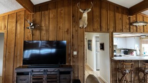 Ein Holzinterieur mit einem aufgehängten Hirschgeweih, einem Flachbildfernseher und einer Bar mit Hockern.