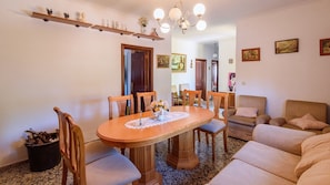 A dining area with a wooden table and chairs, a sofa, and a fireplace.