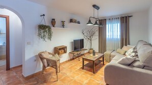 A living room with a sofa, a coffee table, a TV, and a wicker chair.