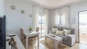 Ett modernt vardagsrum med en grå soffa, ett soffbord och en matplats med ett bord och stolar.