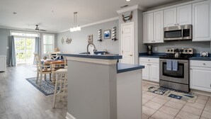 A modern kitchen with white cabinets, stainless steel appliances, and a blue countertop. - Beautiful Sunset Island 3 BR Condo, FREE Linens &Towels, includes 4 Beach Chairs (Ocean City)
