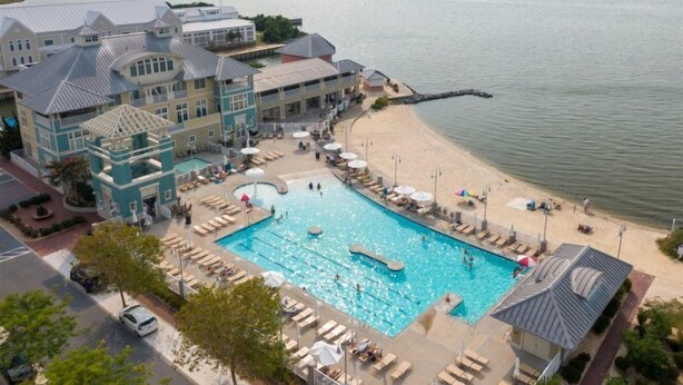A resort with a large pool, beach area, and a building with multiple balconies. - Beautiful Sunset Island 3 BR Condo, FREE Linens &Towels, includes 4 Beach Chairs (Ocean City)