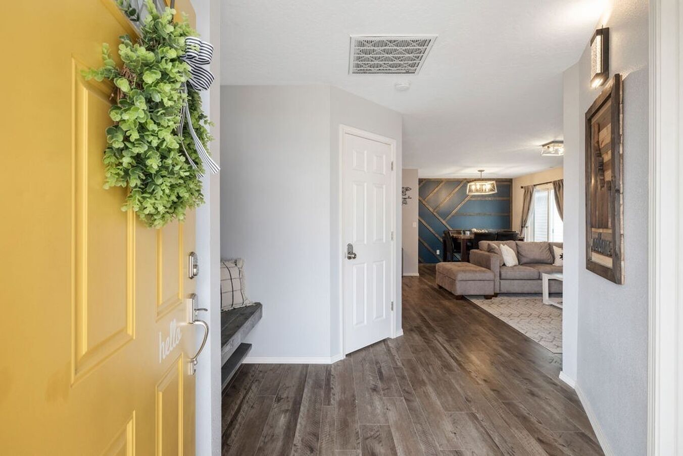 Ein Flur, der in ein Wohnzimmer mit Sofa und Essbereich führt.