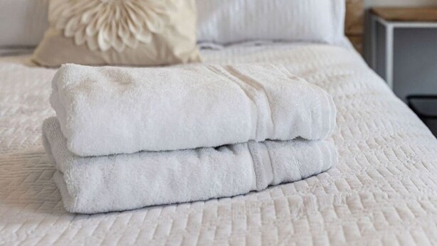 Una cama bien hecha con ropa blanca y una almohada decorativa.