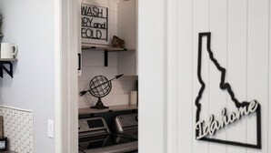 Una cocina con estufa de acero inoxidable, un globo terráqueo y un cartel que dice 'Lavar, secar y doblar'.