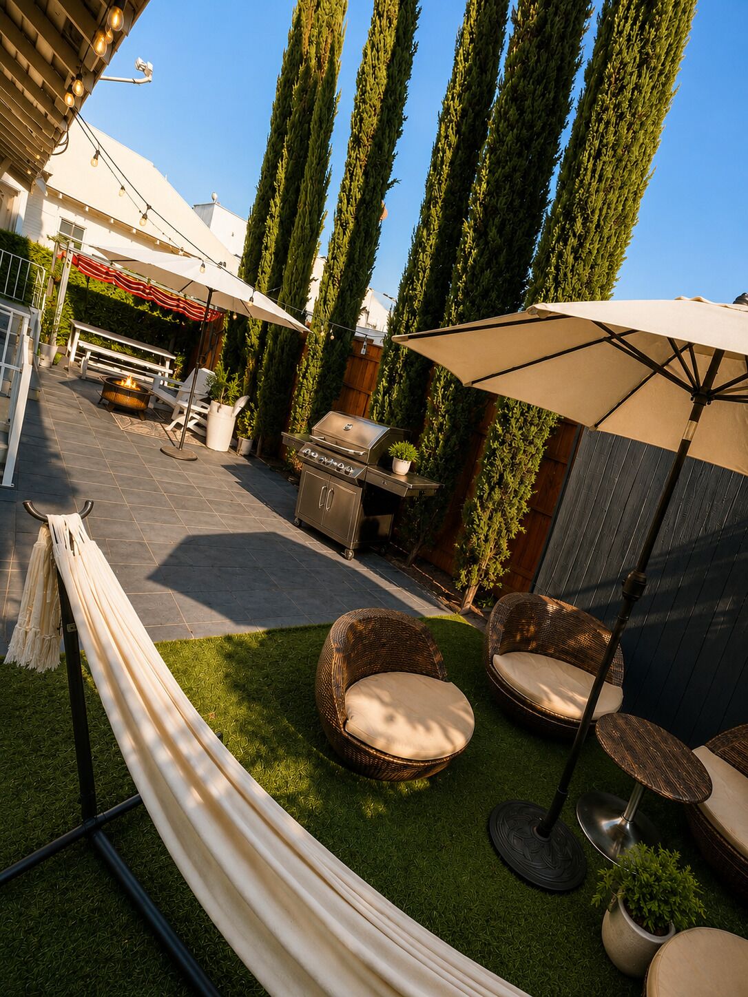 Une terrasse avec des meubles d’extérieur, un barbecue et un hamac.