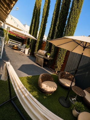 Une terrasse avec des meubles d’extérieur, un barbecue et un hamac.