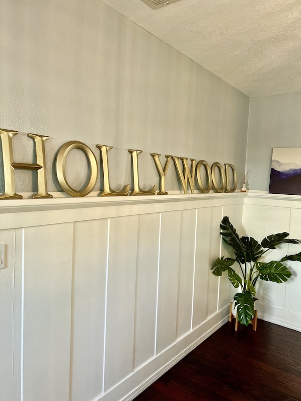 Eine Wand mit großen, goldenen Buchstaben, die "HOLLYWOOD" auf einer weißen, profilierten Wand buchstabieren.