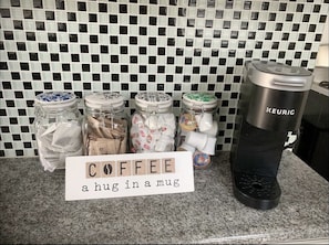 Eine Kaffeestation mit Kaffeebohnen in Gläsern und einer Keurig-Kaffeemaschine.