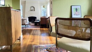 Een woonkamer met houten vloer, een bank, een stoel en een open haard.