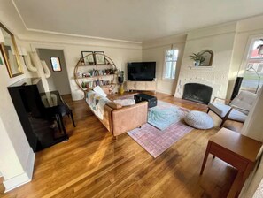 Ein Wohnzimmer mit einer Couch, einem Fernseher, einem Kamin und einem Bücherregal.