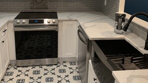 A kitchen with white cabinets, a stainless steel microwave, a stove, and a dishwasher. - Beach Getaway (Long Beach)