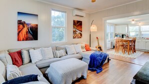 Ein geräumiges Wohnzimmer mit einer großen Couch, einem Essbereich mit Holzkohlen und einem Deckenventilator.