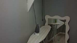 A room with a mirror, ironing board, and a ceiling light fixture. - The Jones Suites (Freeport)