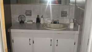 A bathroom with a white sink, mirror, and cabinets. There is a patterned rug on the floor. - The Jones Suites (Freeport)