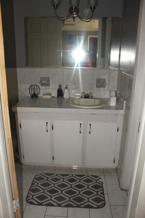 Bathroom features a single sink, vanity with cabinets and mirror, and a tiled floor.