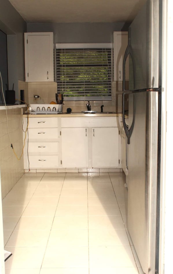 Compact kitchen with a stainless steel refrigerator, sink, and countertop with kitchen essentials.