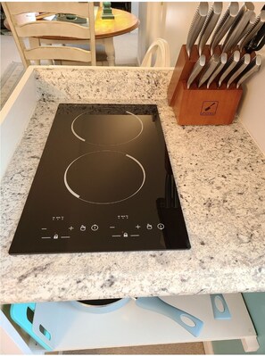 Kitchen area features a cooktop with two heating zones, a drawer unit, and a knife block.