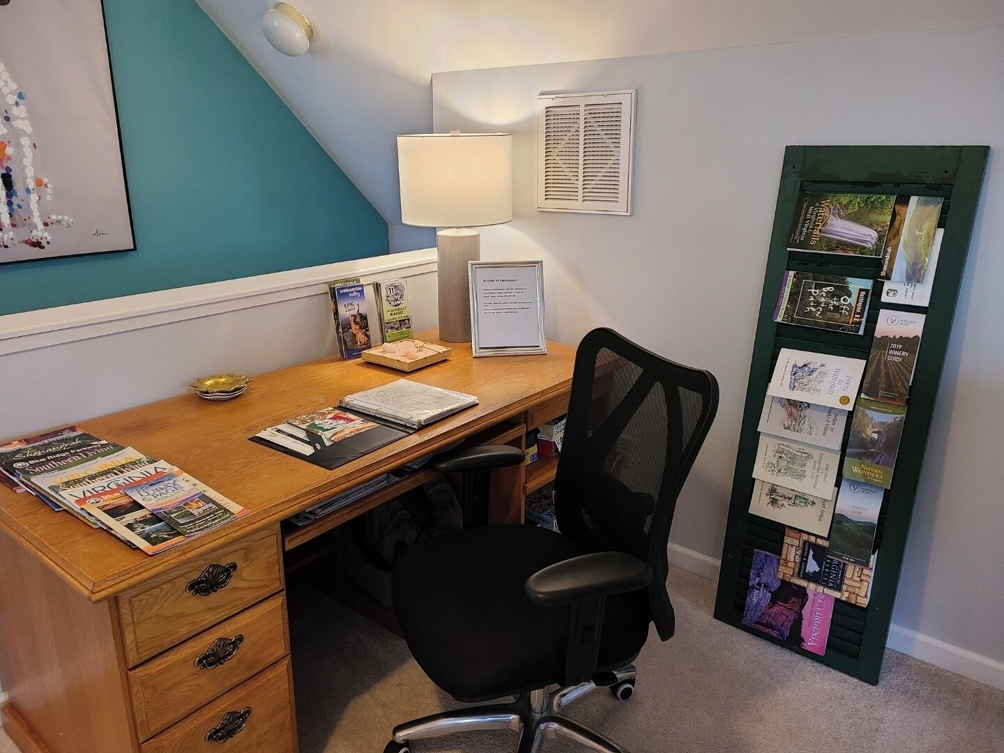 Une salle d’étude équipée d’un bureau en bois, d’un fauteuil de bureau noir et d’un tableau d’affichage où sont accrochés divers documents et brochures.
