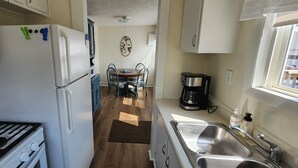 Een kleine keuken met een fornuis, koelkast en spoelbak.