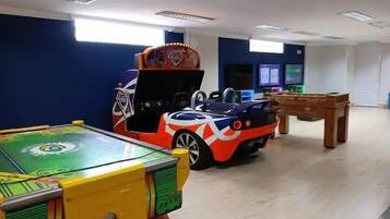 Una habitación con mesa de billar, un coche para niños y una mesa de futbolín.