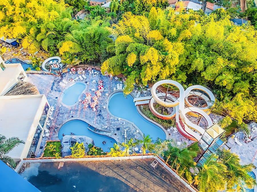 Ein Luftbild eines Resorts mit mehreren Schwimmbecken, Wasserrutschen und üppiger Vegetation.